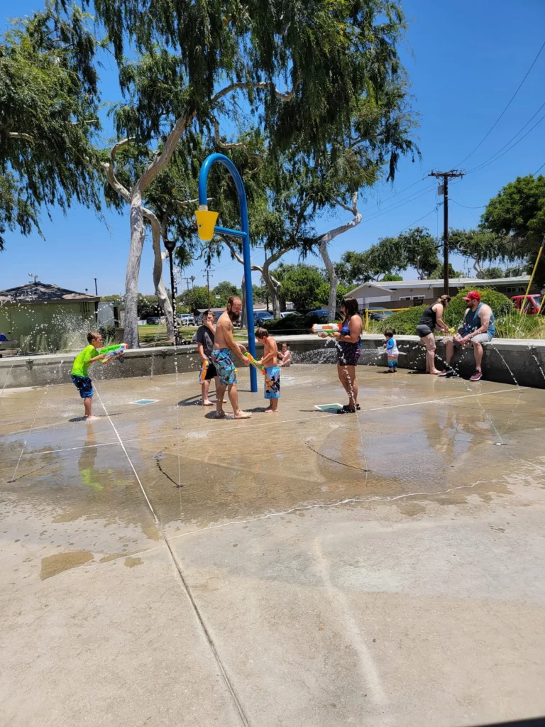 Happy family laughing and playing together in the sparkling waters of Adlena Park.