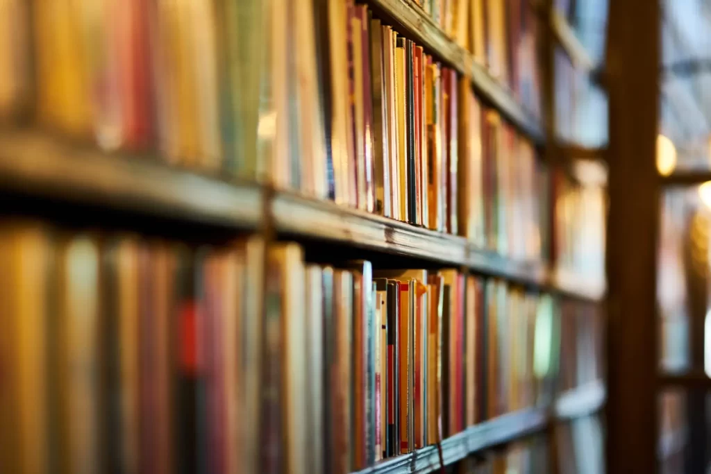  Close-up view of the spines of books lined up on a wooden shelf, showcasing the intricate details of book binding.