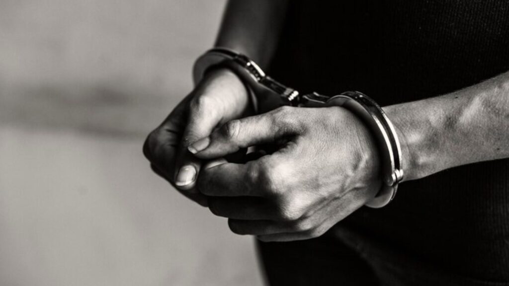 A black and white photo of a person holding handcuffs, symbolizing the consequences of tax evasion