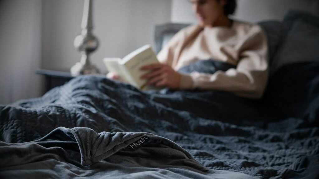 A man engrossed in a book while lying in winter bedding & weighted blankets