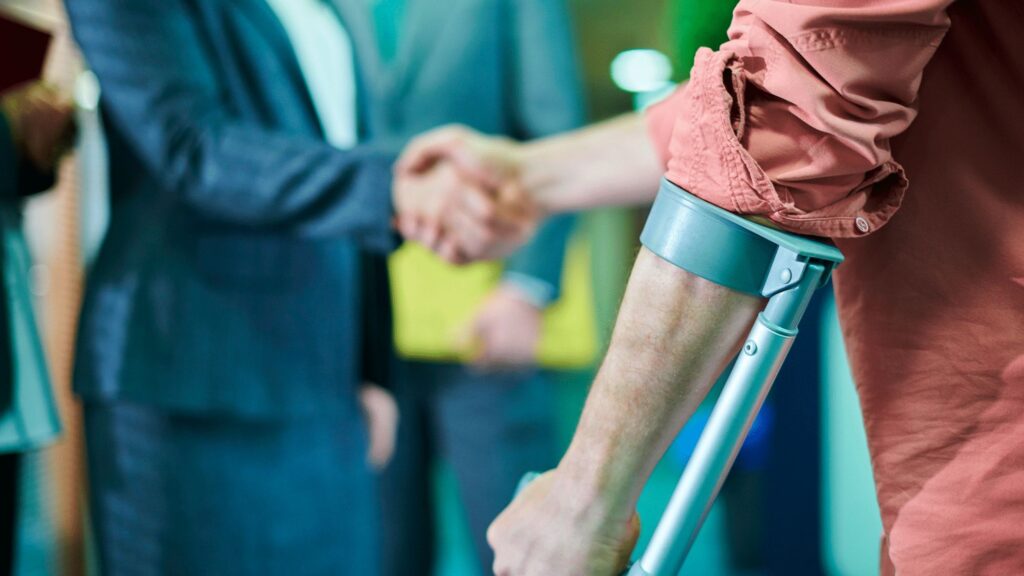 A man with crutches warmly shaking hands, showcasing the backdrop of personal injury fraudsters