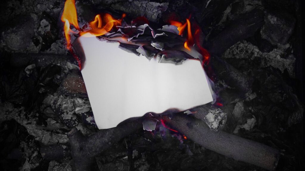 A piece of paper burning in a fire, representing burning waste removal