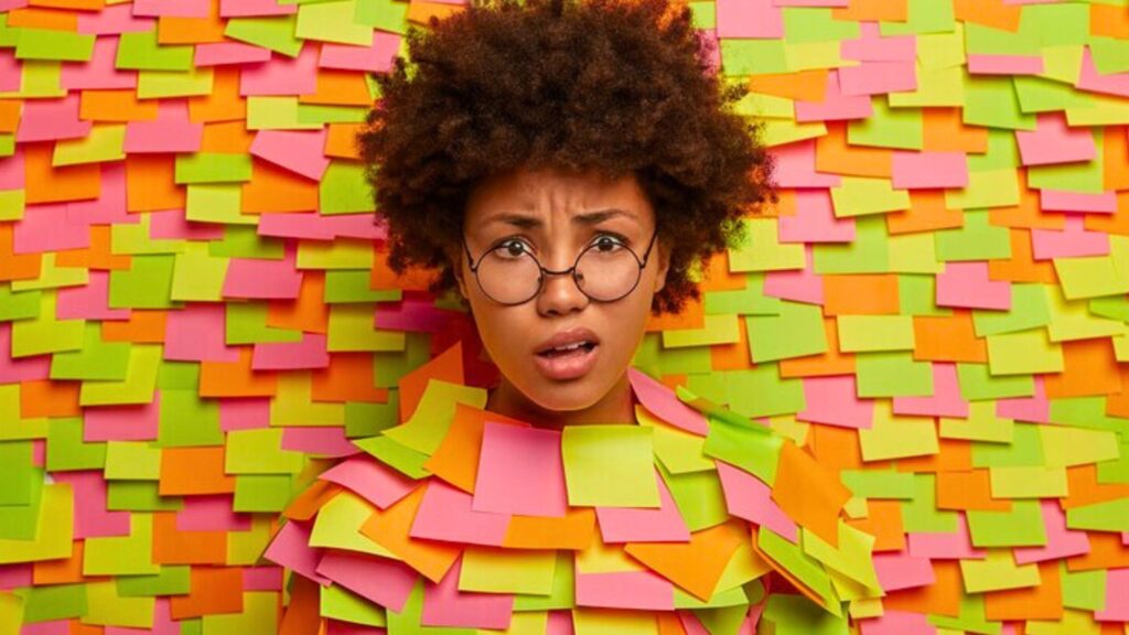A woman with glasses surrounded by numerous sticky notes, handling complicated child custody problems