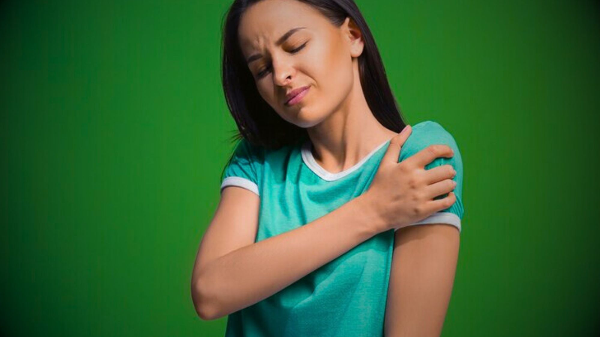 A woman with her arm on her shoulder, expressing chronic shoulder pain